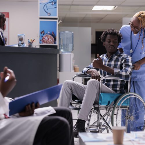 Person with chronic disability in waiting room at health center facility, wheelchair user waiting to attend checkup appointment. Man with physcal impairment doing consultation at medical clinic.